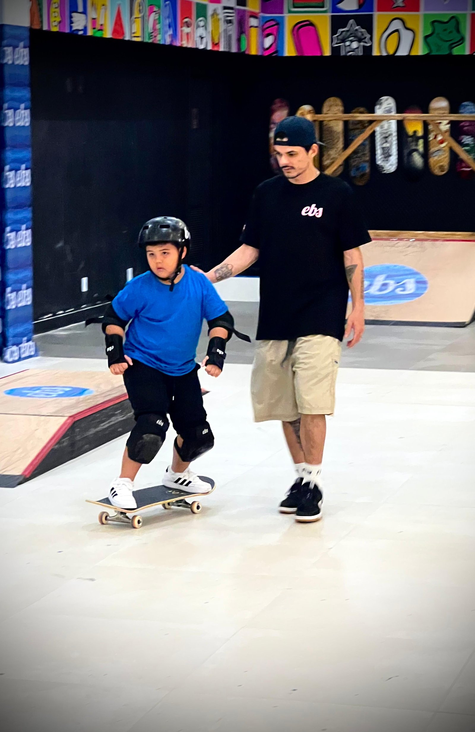 Criança aprendendo skate com acompanhamento